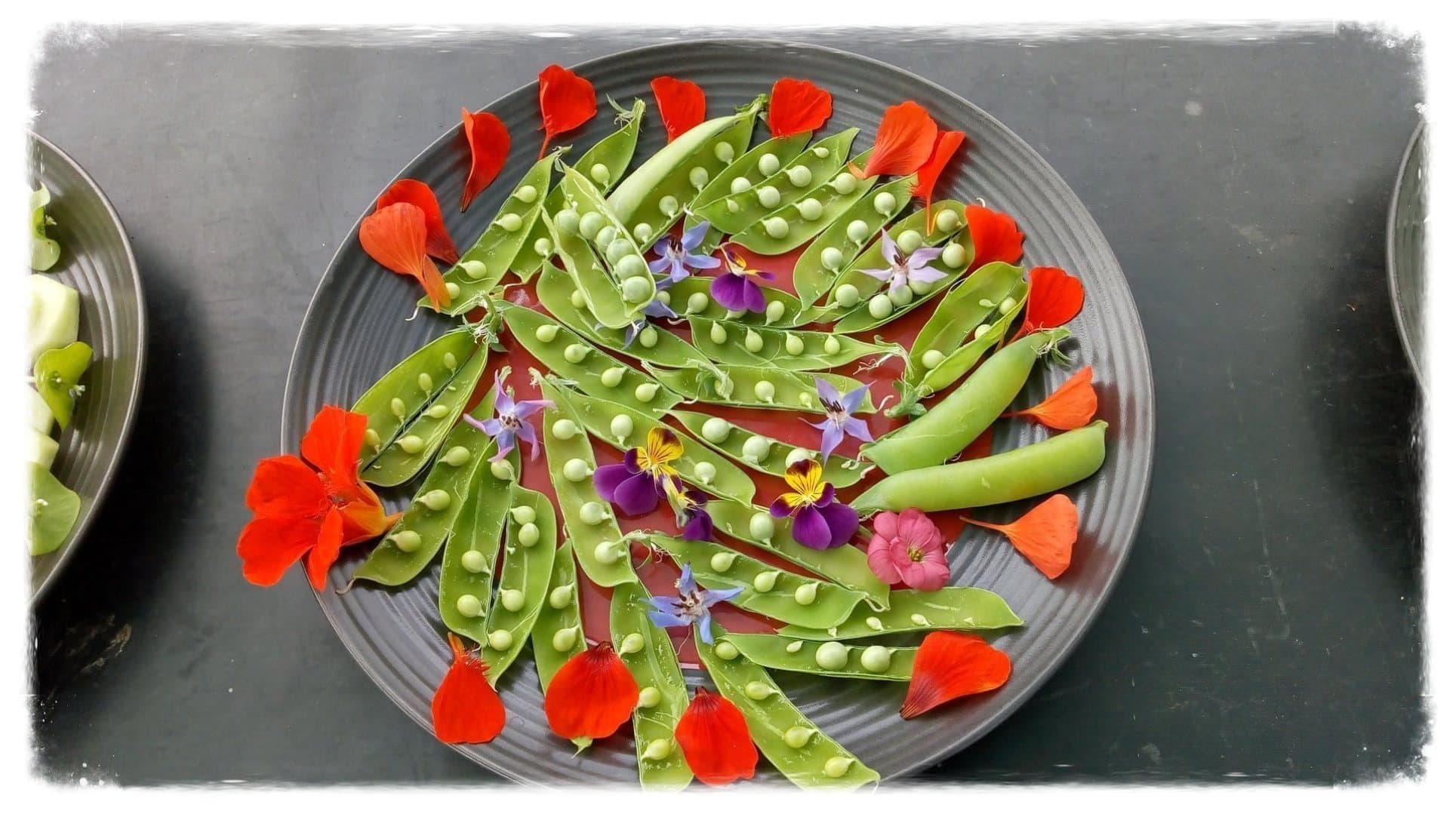 Pois frais et fleurs comestibles dressés dans une assiette